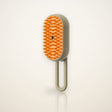 3-in-1 Steam Grooming Brush for Cats and Dogs on a plain warm sand studio backdrop