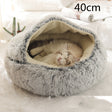 Grey plush round pet bed with the hood raised over the cream lining and a cat asleep inside, the option size printed in the corner