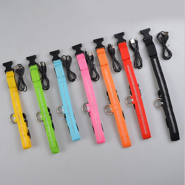 Row of seven unlit collars in yellow, green, blue, pink, orange, red and black, each shown beside a black USB cable