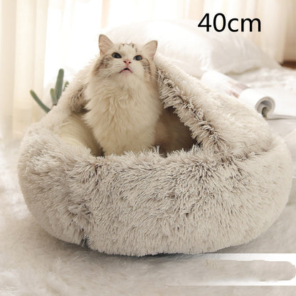 Cream and brown plush round bed with the hood raised behind a long-haired white cat sitting in the opening, the option size printed in the corner