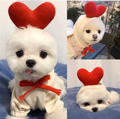Three-panel collage of two different white long-coated dogs in the cream hoodie with a padded red heart on the hood and a red tie, one panel showing that hood worn over a pink floral top