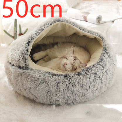 Grey plush round pet bed with the hood raised over the cream lining and a cat asleep, photographed on a white rug with the option size printed in the corner
