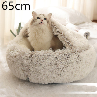 Cream and brown plush round bed with the hood raised behind a long-haired white cat, shown beside a folded magazine with the option size printed in the corner