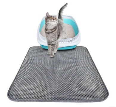 Grey honeycomb litter mat on a white background with a tabby cat stepping out of a white and teal litter tray behind it